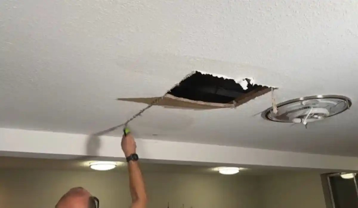 Technician patching a ceiling access panel after a water leak