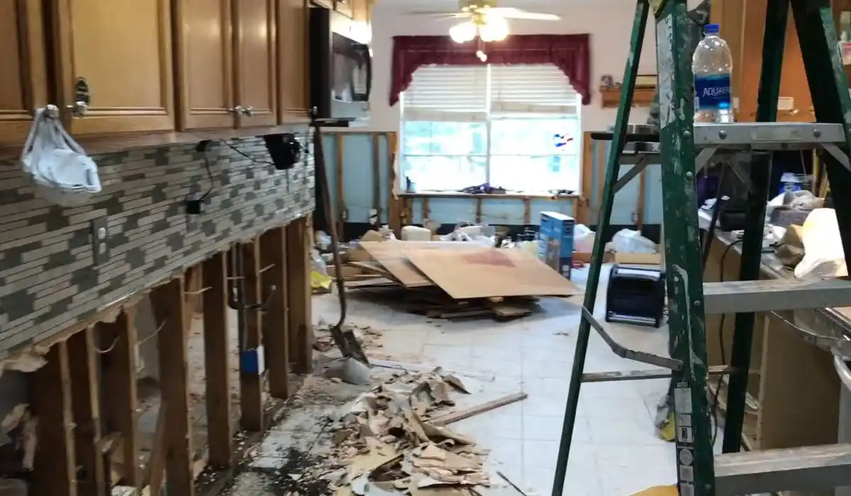 Kitchen under active demolition after flood damage, with cabinets and drywall removed