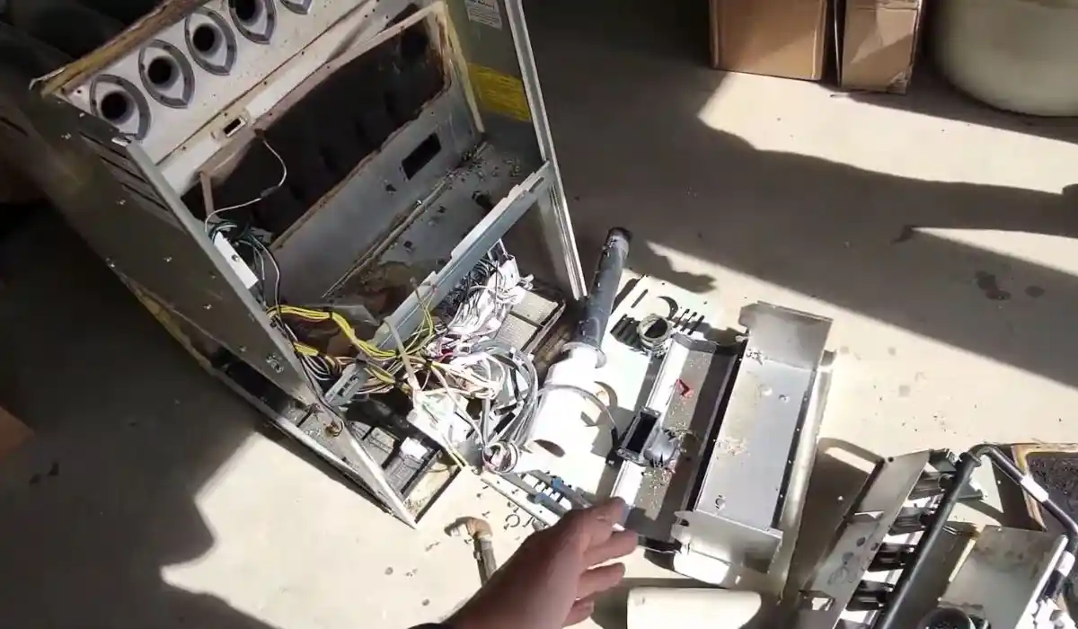 Technician working on a disassembled, soot-covered furnace component