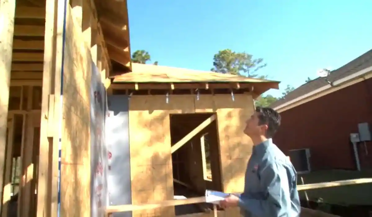 Homeowner inspecting storm-damaged framing on a house exterior