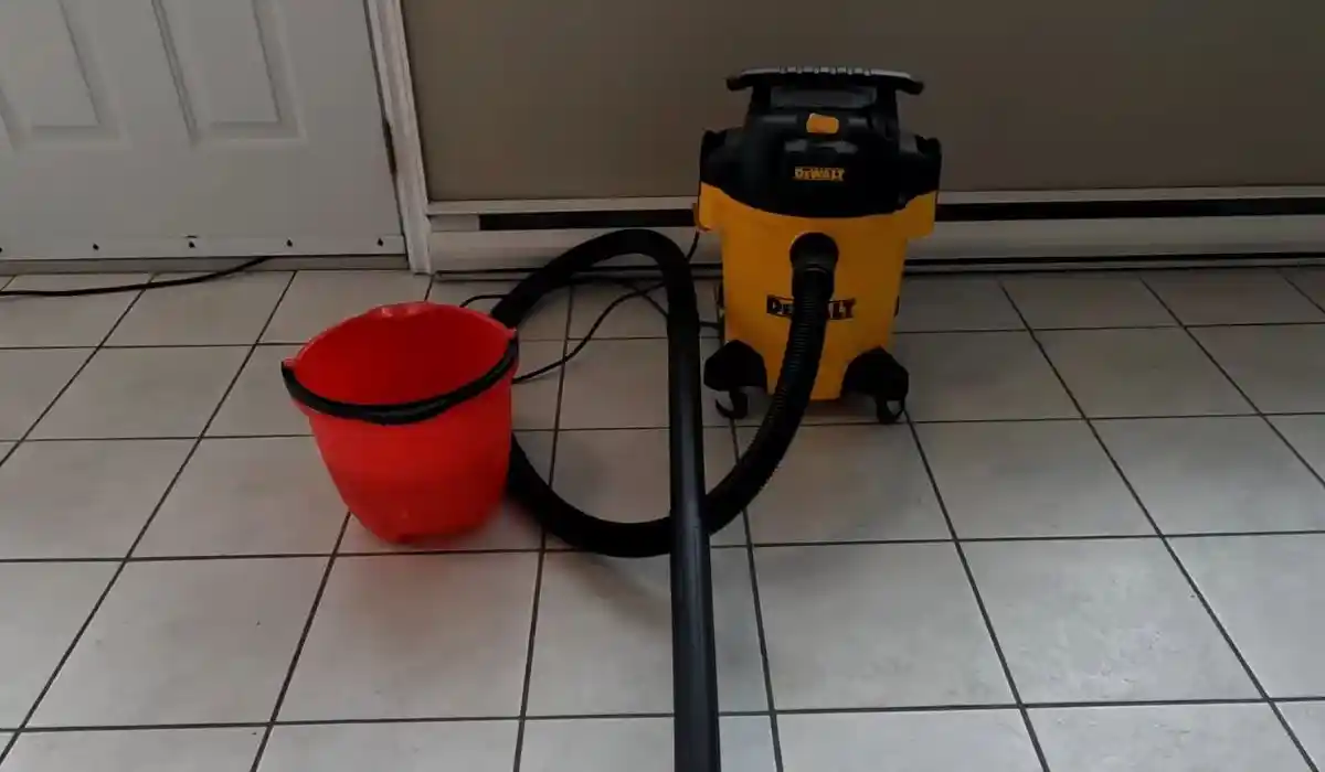 Wet-vac and bucket set up on a kitchen tile floor for water extraction