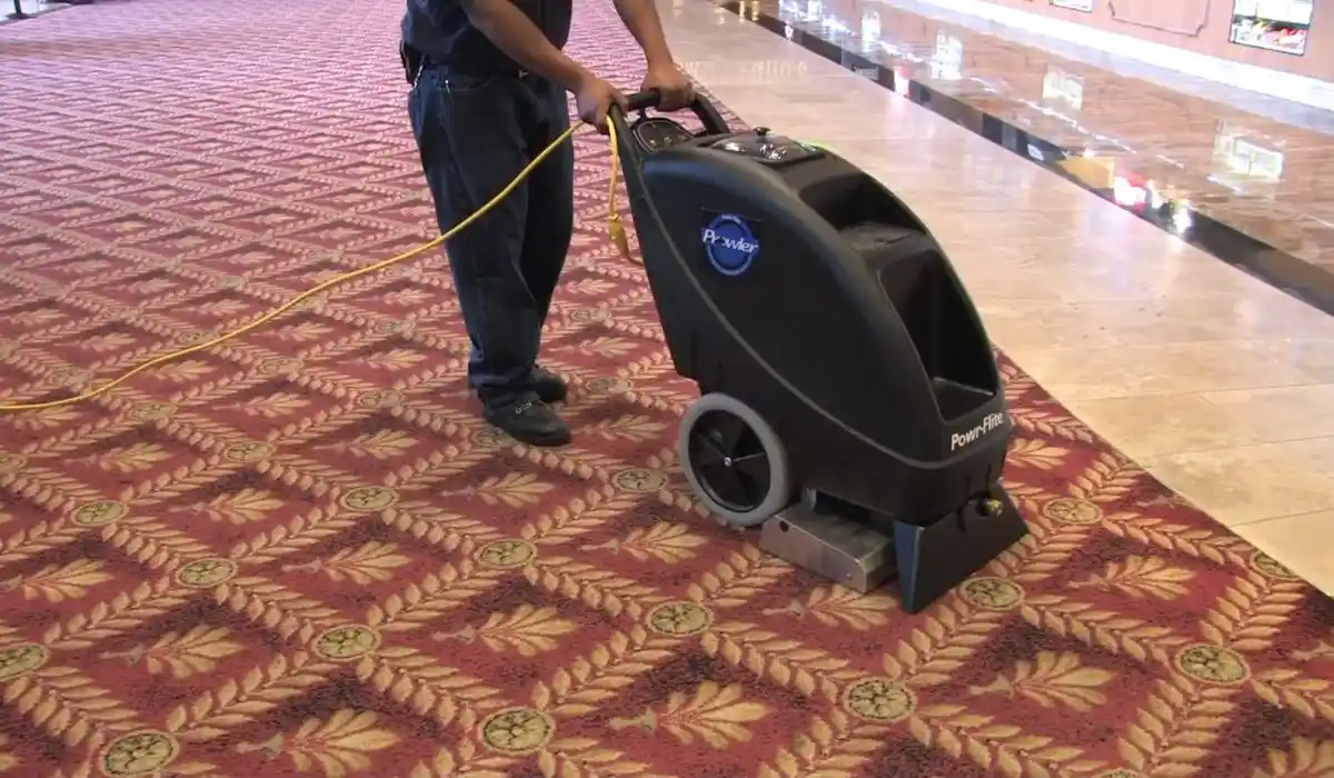 Technician operating a floor extraction machine on commercial carpet